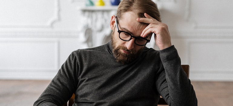 man holding his head, deciding on the course of his addiction therapy