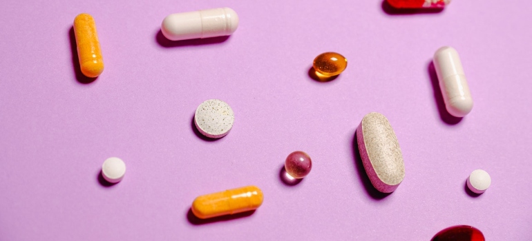 Colorful pills on pink background.